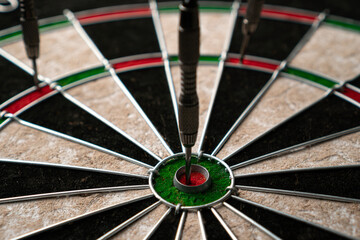 Three darts hit the dartboard. Lucky - one of the darts hits the bull's eye. The concept of winning and luck. Close-up, angled view