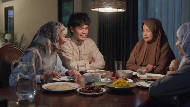 Happy Asia muslim parent and their kids Ramadan dinner together in dining room at home. Family of two generation catering celebration end of Eid al-Fitr togetherness at home. Hari Raya family reunion.