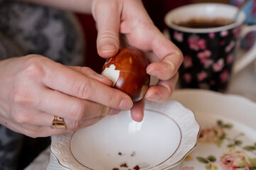 Woman female hands peeling the eggshell of easter naturally colored egg after breaking it
