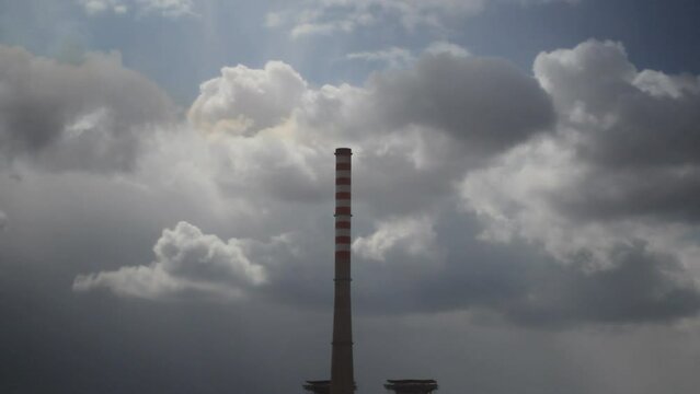 A large chimney from a thermal power plant. In the background, heavy clouds are moving slowly.