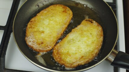 Cooking bread in an egg. Fry in oil in a pan. White stove, cooking breakfast. Black frying pan. There is a lot of fat in the pan. Fatty food, a lot of cholesterol. Fried croutons for breakfast