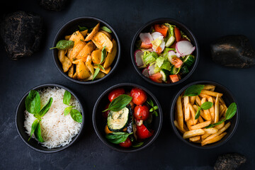 Set of french fries, rice, potato wedges and vegetable salad.