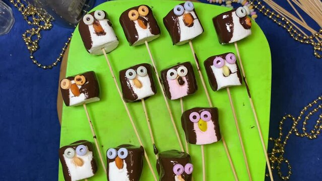 Creative food decoration. Sweet marshmallow penguin sliding on the green chopping board Desserts and sweets. High quality 4k footage