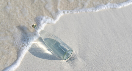 Glass bottle of pure water on the white sand on the Maldives beach