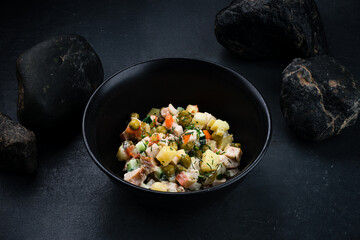 Salad Olivier from boiled potatoes, carrots, green peas, cucumbers, eggs, chicken ham and mayonnaise in bowl.