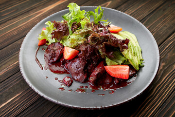 warm salad with liver, avocado, strawberries and lettuce leaves