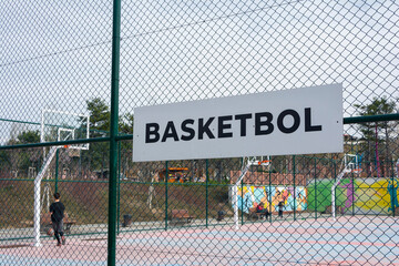 Basketball field sign in Turkish on a fence in a sunny day.