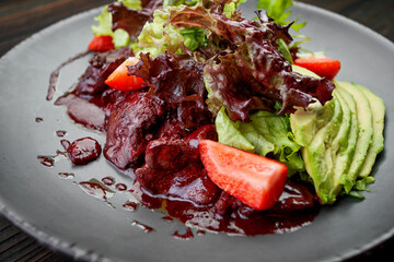 warm salad with liver, avocado, strawberries and lettuce leaves