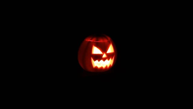 Scary Halloween pumpkin face with glowing candle in the Dark.