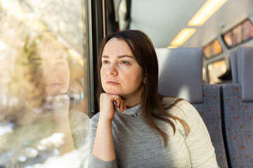Pensive caucasian woman traveler sitting inside train and looking out window.