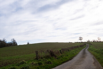 Rural road going up in cloudy weather. Rural landscape in France.