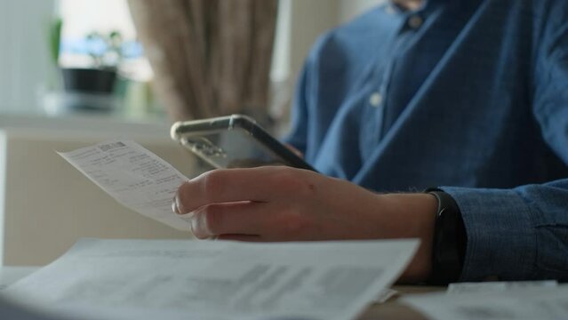 Man pays bills from smartphone scanning qr code of receipts or invoices, close-up