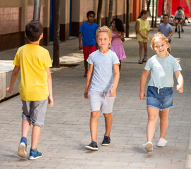 Positive little boy and his sister walking together on the street
