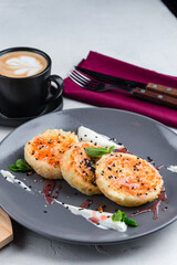 Cheese pancakes with jam, sour cream, sesame seeds, mint and cup of coffee.