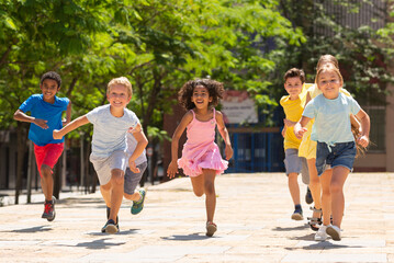Group of joyful children running down the summer city street © JackF