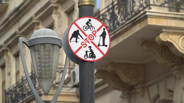 STOP sign with a picture of a bicycle, scooter and skateboard.