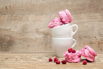 Sweet pink marshmallow in cup with fresh raspberry with copy space on wooden background, Valentines Day food concept