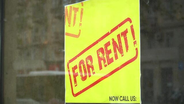 FOR RENT written in red on a yellow banner affixed to glass
