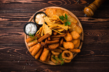 Snack fried chicken fillet, crispy onion rings, cheese sticks, garlic croutons, nachos, sauces, spices and greens.
