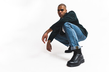 stylish Afro-American young man hunkering down and posing, full shot studio shot. High quality photo