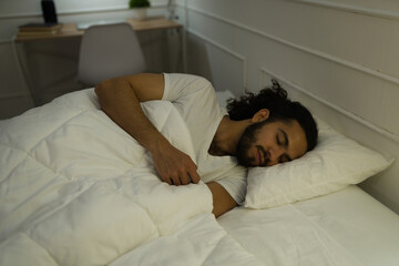 Rested young man in bed falling asleep