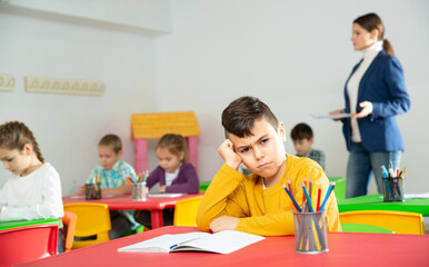 Portrait of tired schoolboy sitting in classroom elementary school