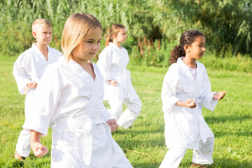 Naklejka na ściany i meble Barefoot kids doing kata during outdoor karate training.