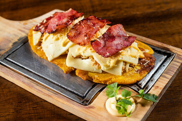 Green plantain patacon with shredded chicken, cheese and bacon - Colombian street food