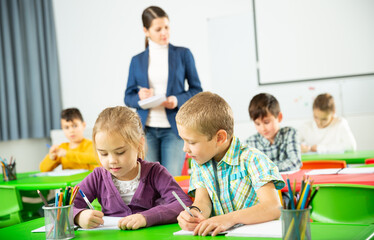 Happy pupils chattering sitting at lesson in elementary school
