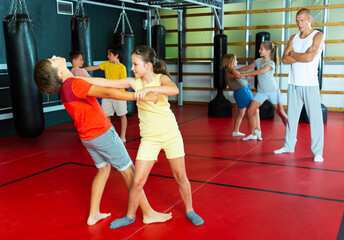Children practicing self defence technique in pairs at gym