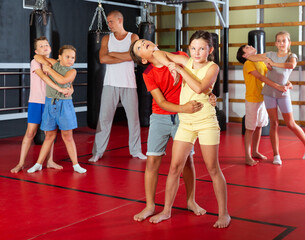 Fototapeta na wymiar Young children working in pair mastering new self-defense moves at gym