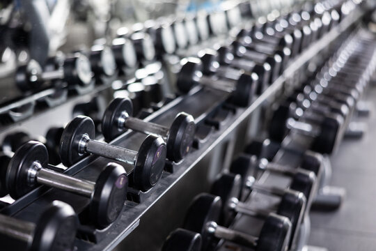 Dumbbells of different weights laid out on racks in gym