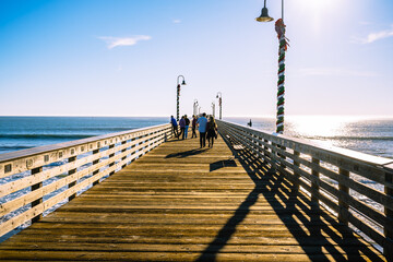 Obraz premium A long wooden pier, and walking people. Cayucos pier, California Central coast