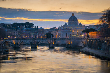 Cityscape with Sant Angelo bridge and St. Peter's cathedral at sunset with city lights in Rome,...