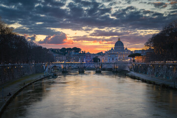 Cityscape with Sant Angelo bridge and St. Peter's cathedral at sunset with city lights in Rome, Italy