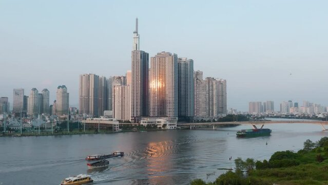 Drone aerial shot of Saigon River in Ho Chi Minh city, sunrise reflecting in modern glass buildings. Background, b-roll shot