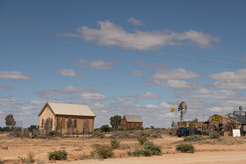 Silverton, New South Wales, Australia - March 8 2023: Wesleyan Methodist Church, former St Carthage Catholic Church and windmill. Blue sky with white, fluffy clouds