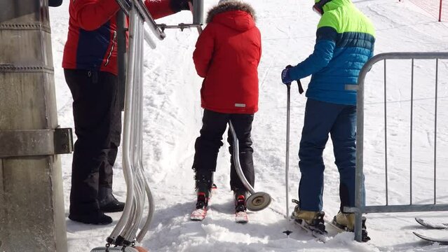 Skier loading a poma (button, drag) surface lift on white snow at a mountain resort in winter season.