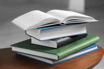 Stack of hardcover books on wooden coffee table indoors, closeup