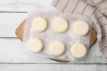 Uncooked cottage cheese pancakes on white wooden table, top view