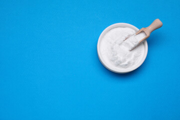Bowl of sweet powdered fructose on light blue background, top view. Space for text