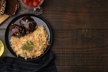 Plate with sauerkraut, chicken and products on wooden table, flat lay. Space for text