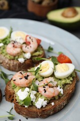 Delicious sandwiches with guacamole, shrimps and eggs on plate, closeup