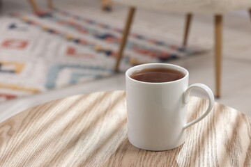 White mug of tea on wooden table indoors, space for text