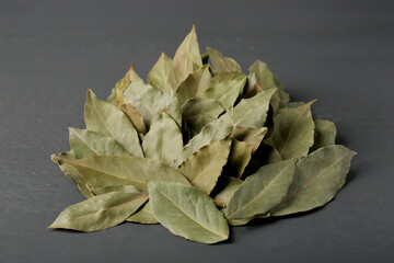 Pile of aromatic bay leaves on gray wooden table