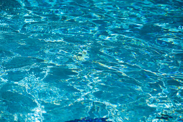 Background of blue water in swimming pool with sun reflection, ripple water wave in pool. Clear water background.