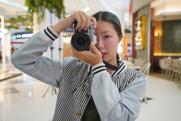 Young female photographer taking photos using a mirrorless camera.