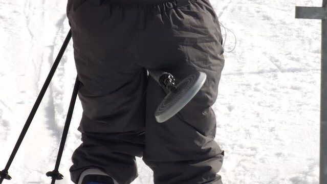 Skier loading a poma (button, drag) surface lift on white snow at a mountain resort in winter season.