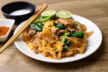 Thai food (Pad See Ew), Stir fried rice noodles soy sauce with pork, egg and kale on wooden background