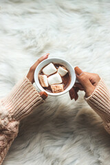 Close-up image, A tasty hot melted chocolate with tiny marshmallows cup in a woman's hand. Winter drinks concept